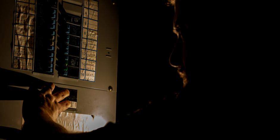 person checking breaker box of home in the dark during a power outage at home