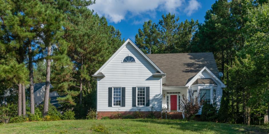 small white house against tall trees forest