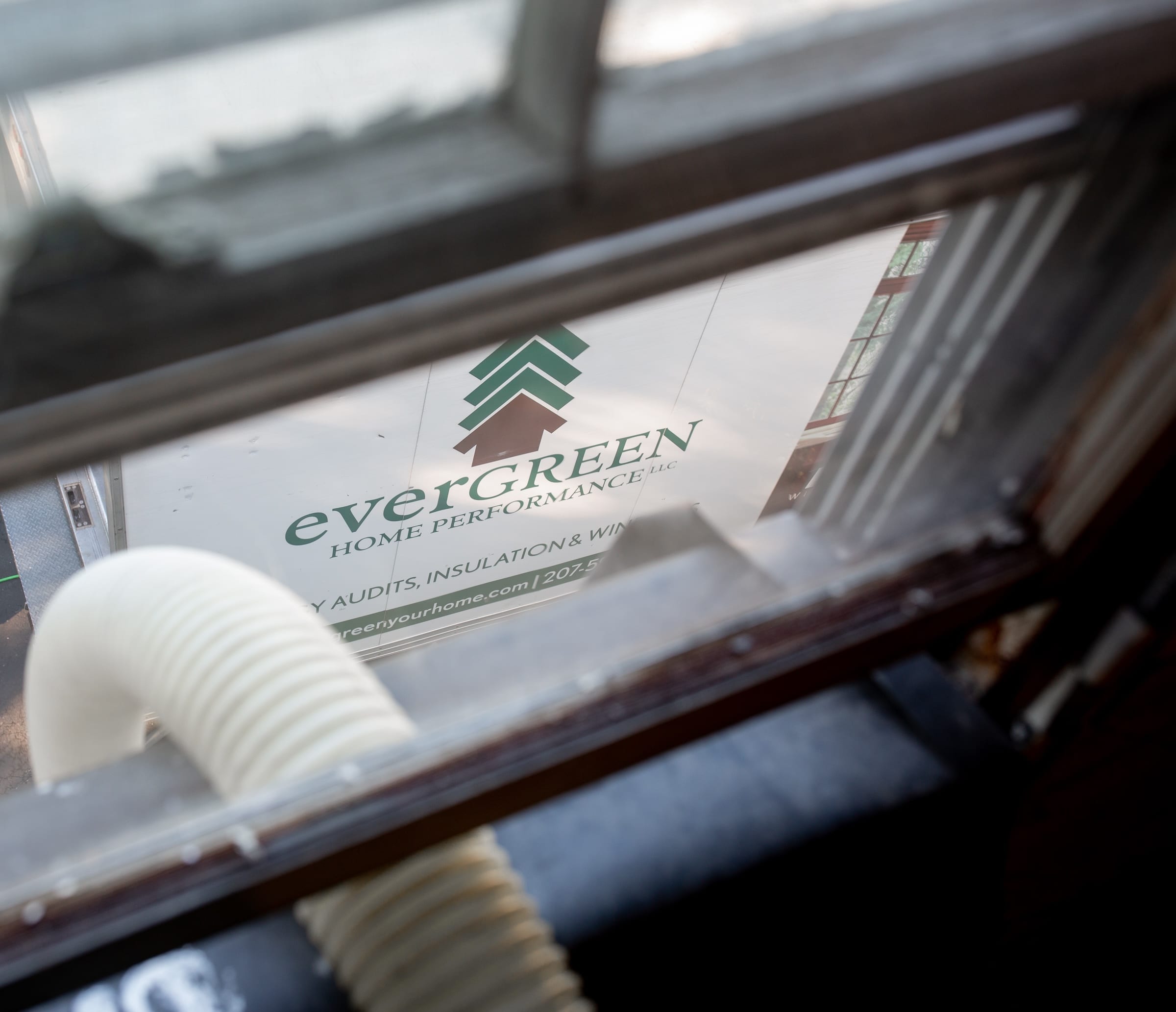 Hose going out through an upstairs window down to the Evergreen Home Performance truck parked in front of the house