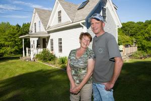 Happy homeowners standing together in front of their house after completing exterior renovation and foundation improvement work