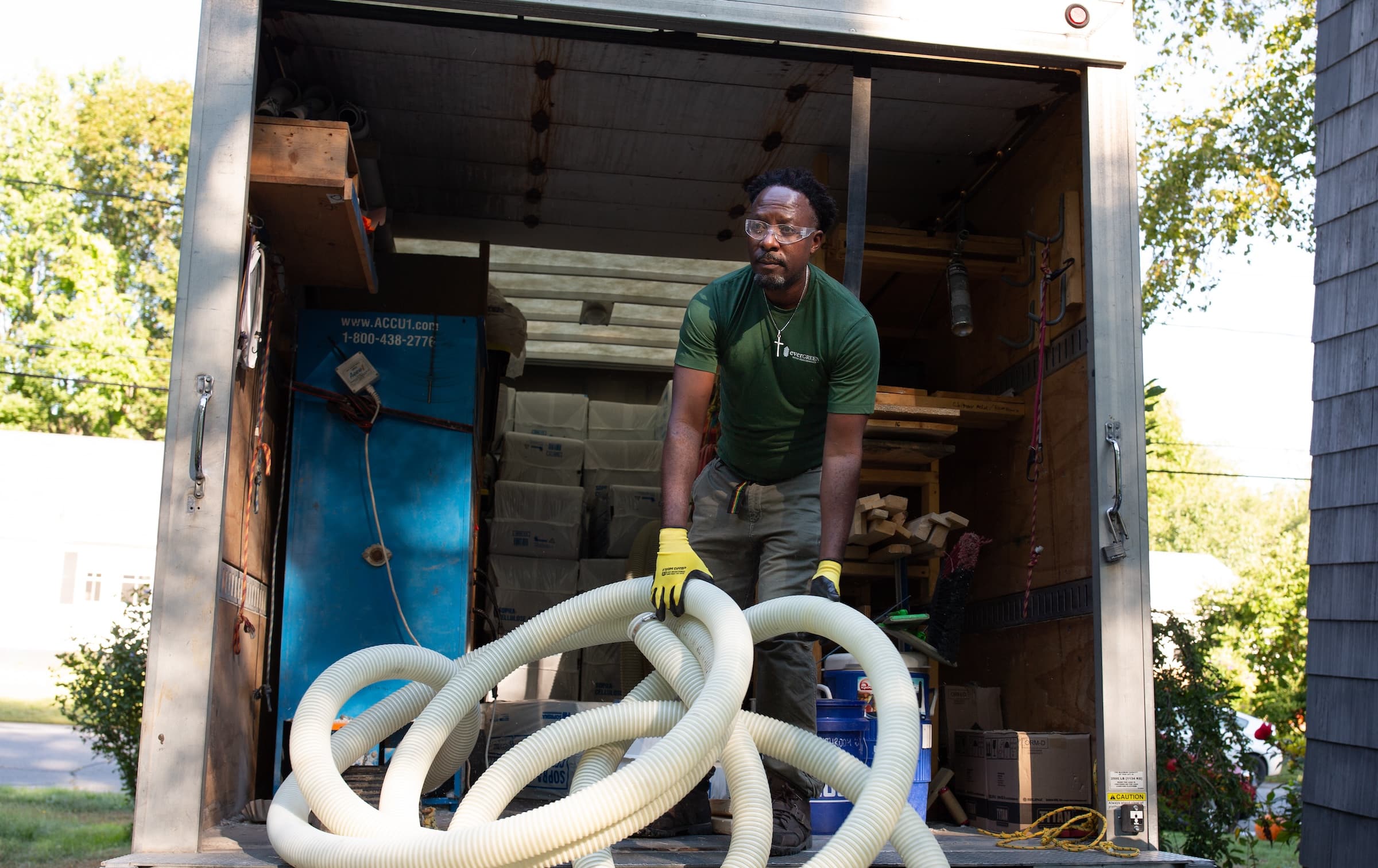 Evergreen team member taking equipment and blown insulation hose out of truck at job site