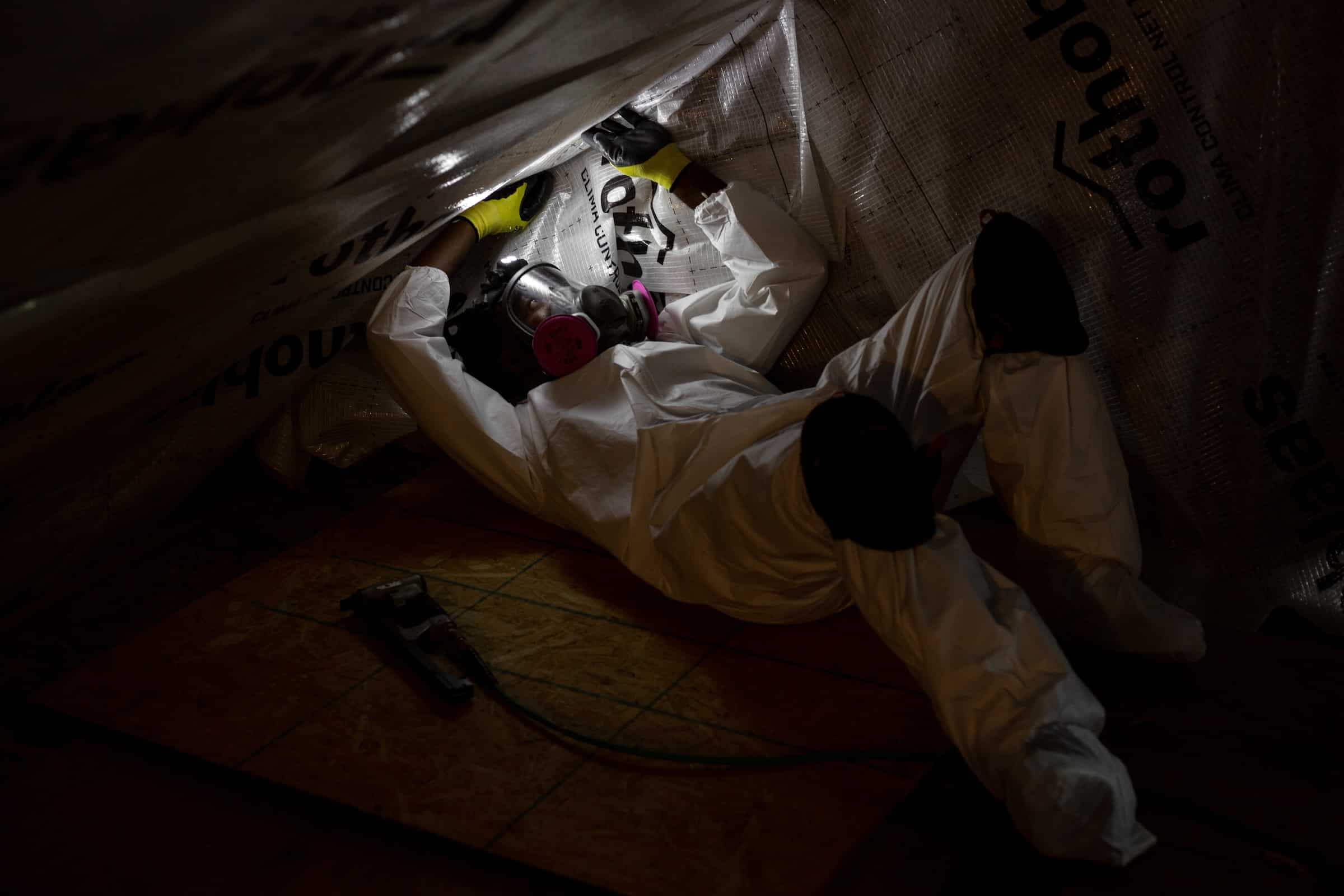 Evergreen team member setting-up climate control net fabric in attic