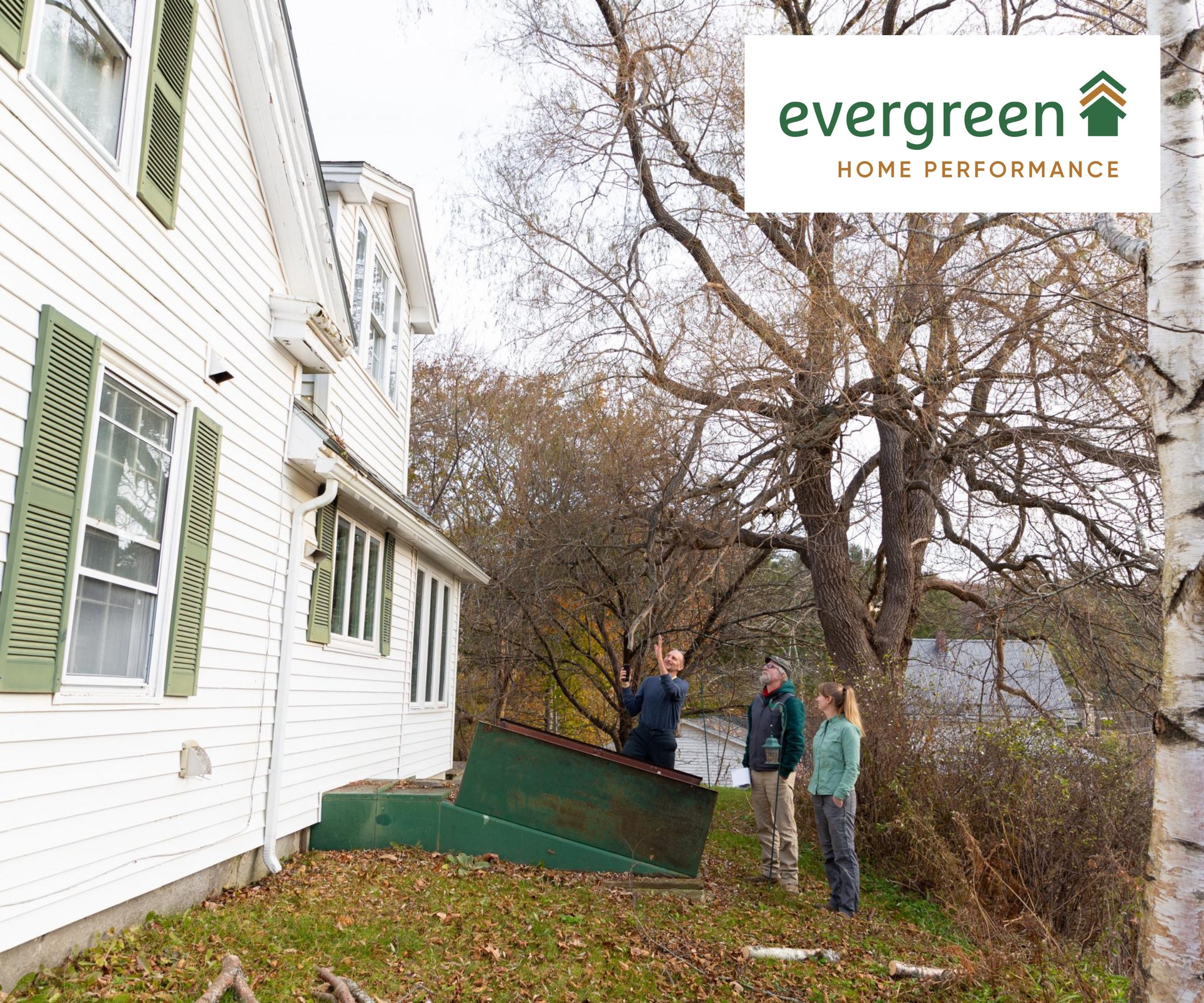 Evergreen Home Performance Team Looking Outside Of A Basement Hatch In The Back Yard Of A House