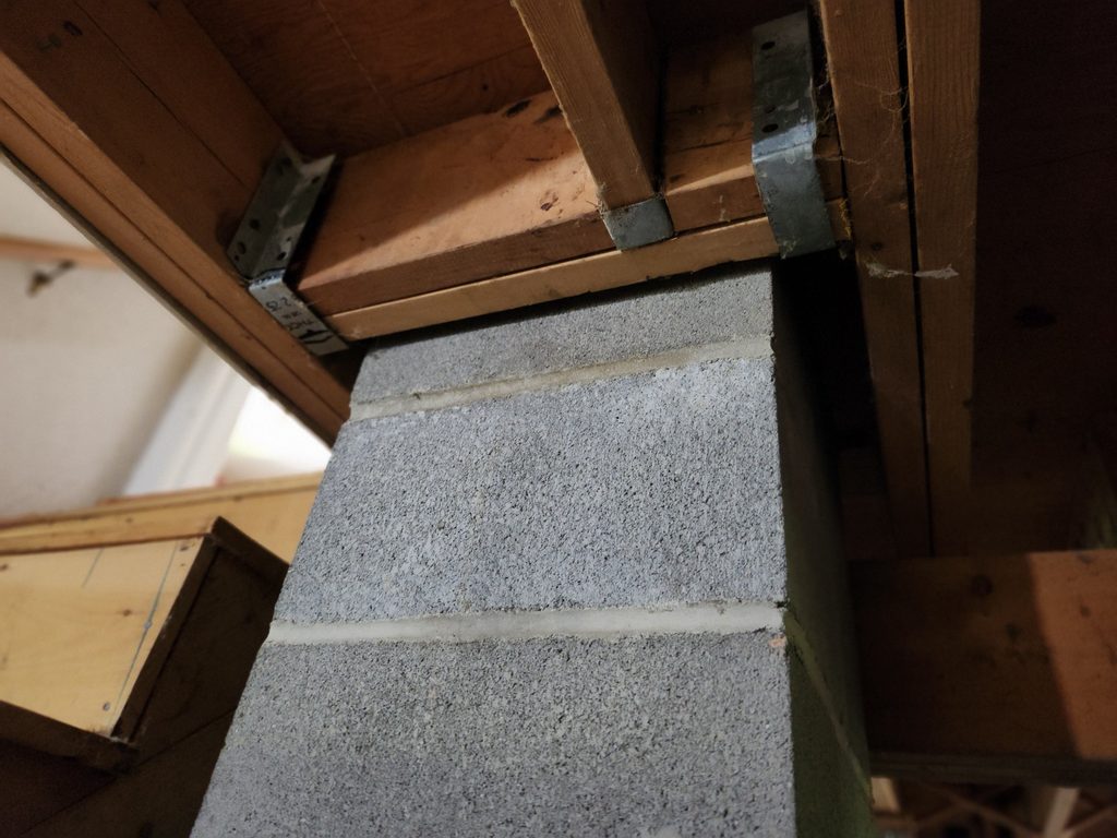 Concrete block chimney meeting the floor framing in the basement before air sealing