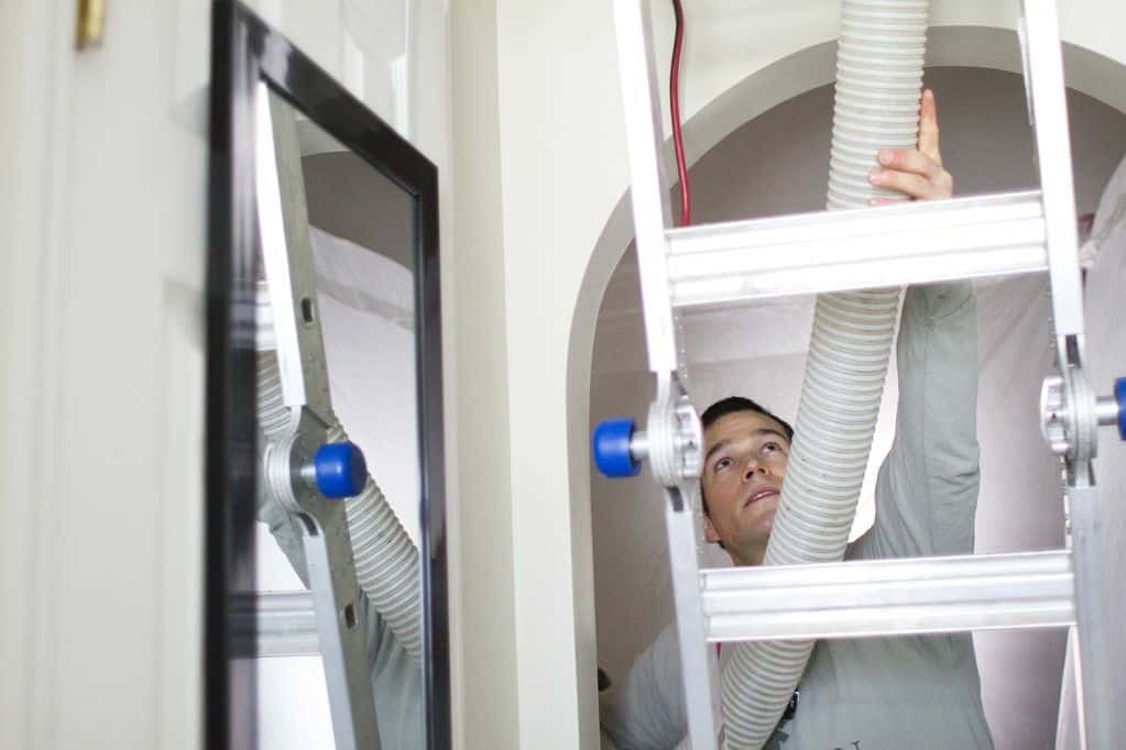 Evergreen crew member feeding an insulation hose up to an attic hatch