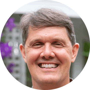 Richard Burbank of Evergreen Home Performance smiling outdoors in front of purple flowers